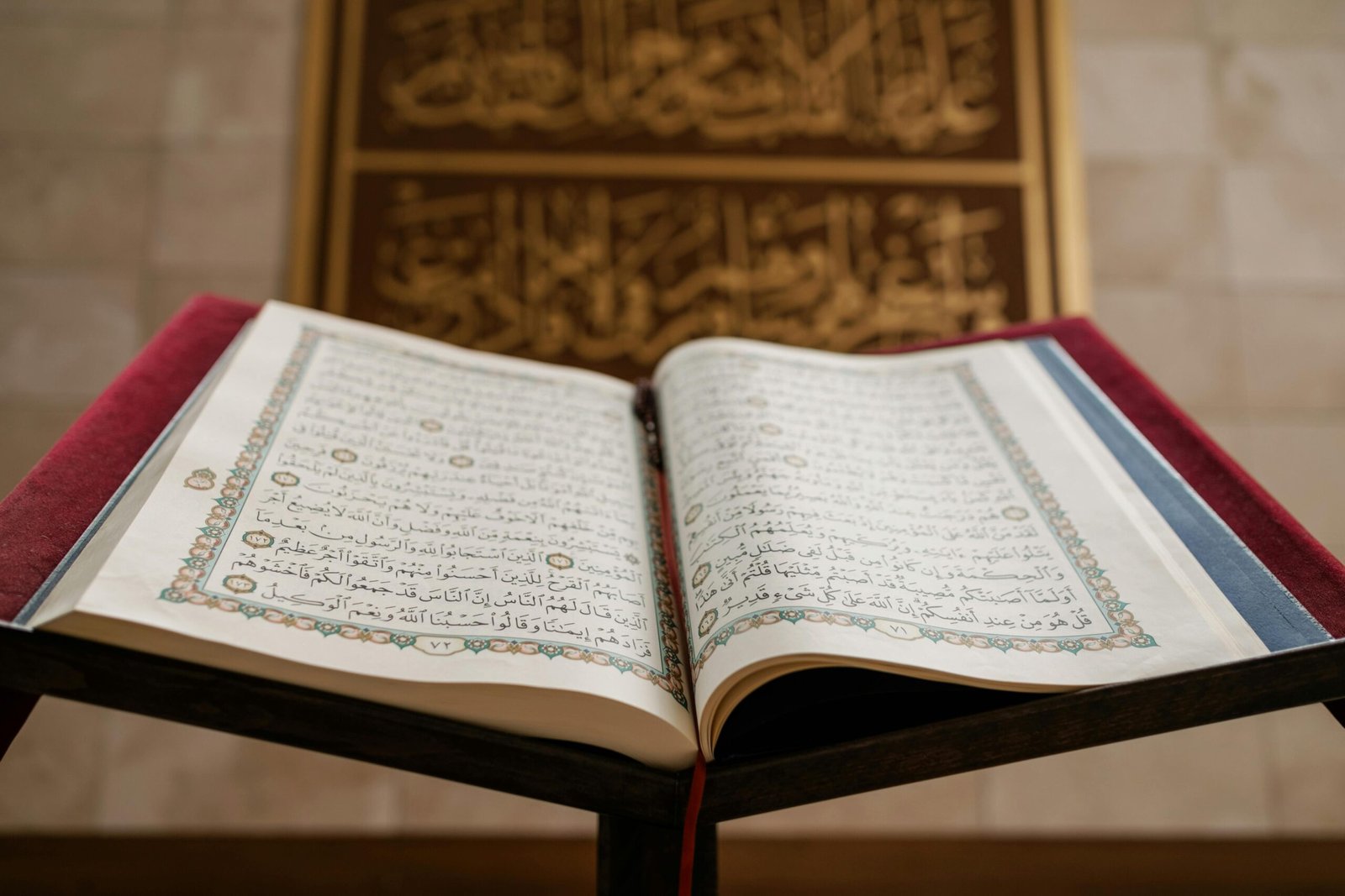 Close-up of an open Quran with ornate pages, featuring Arabic calligraphy in a serene setting.