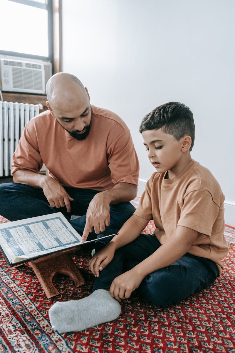 Father and son sitting together, focusing on religious teaching at home. Engaged and peaceful scene.