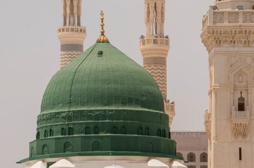 The iconic Green Dome of Al-Masjid an-Nabawi in Medina, Saudi Arabia, with surrounding minarets.